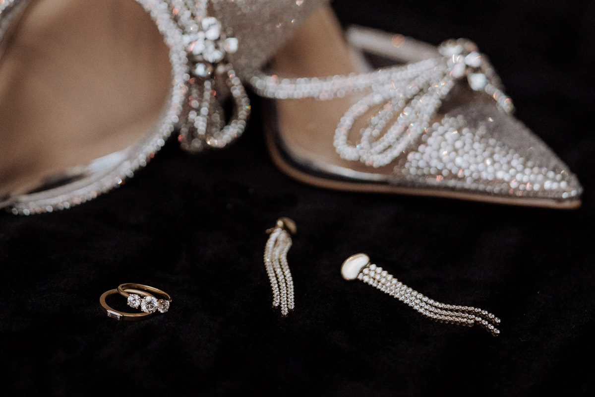 Brautschmuck Ringe, Ohrringe und Brautschuhe im Hintergrund