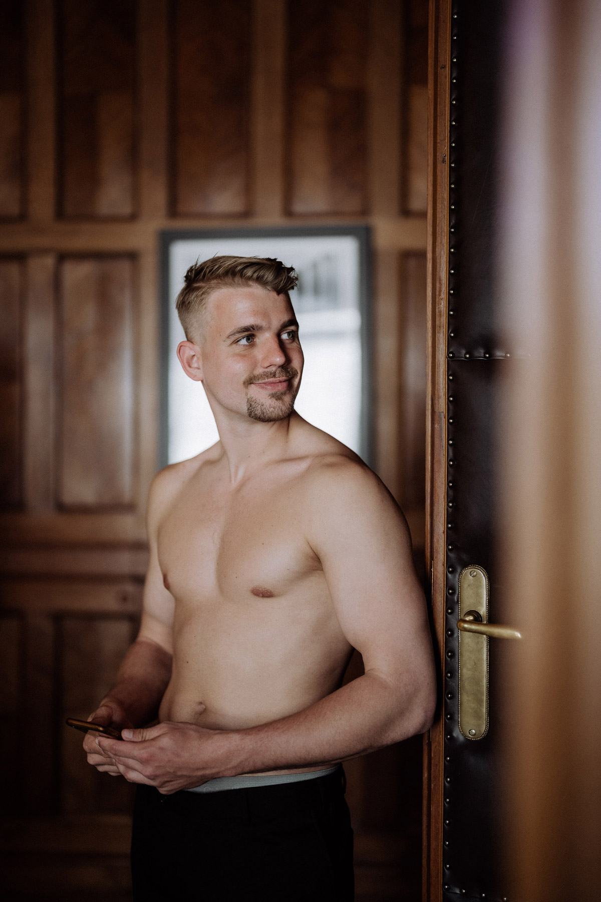 Bräutigam schaut voller Vorfreude durch die Tür in der Bankersuite