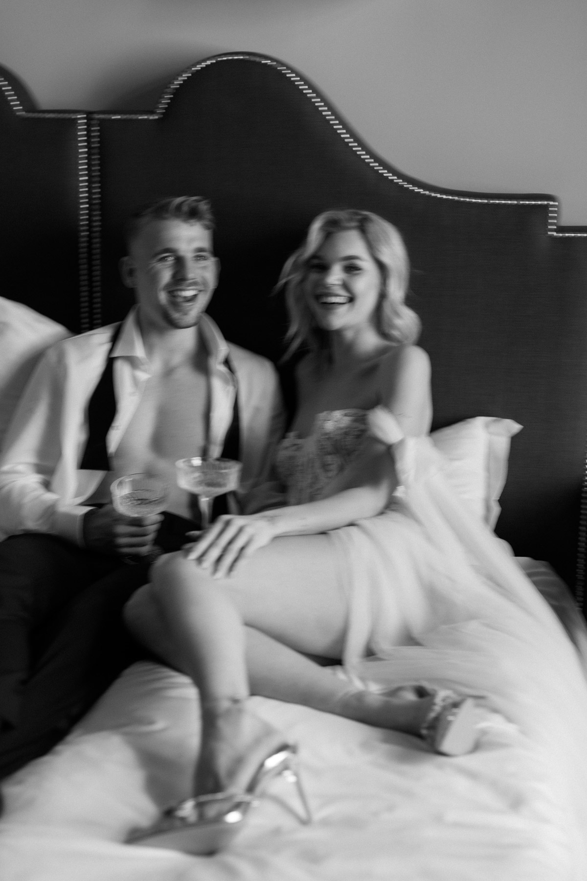 Brautpaar trinkt Champagner im Bett mit künstlerischer Bewegungsunschärfe, Party Vibes und Editorial Style. Foto: Melanie Meißner