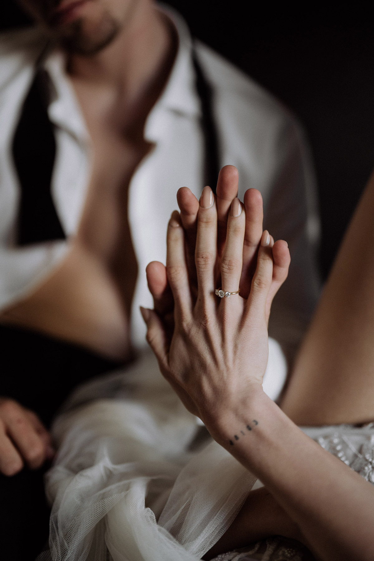 Hände berühren sich ästhetisch mit Fokus und Licht auf Verlobungsring