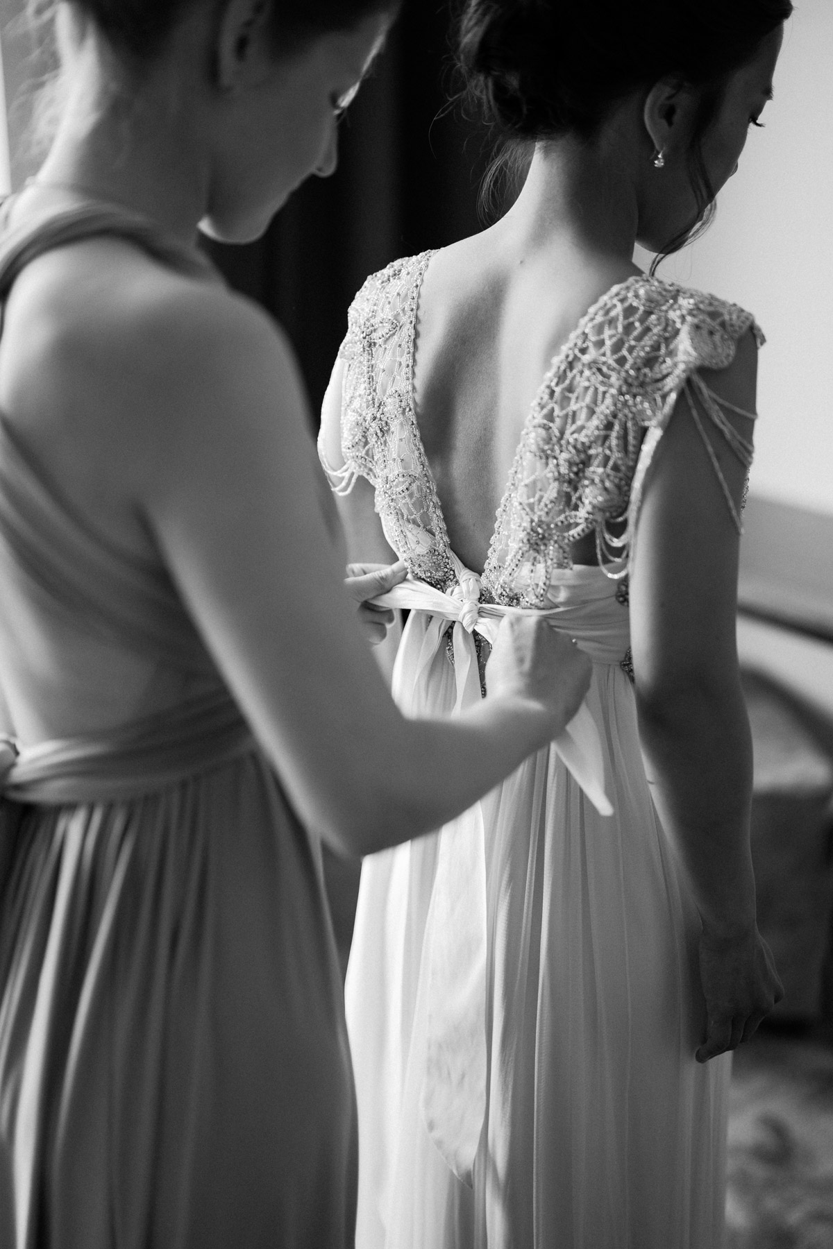 Brautkleid wird am Rücken von Brautjungfer zugeschnürt