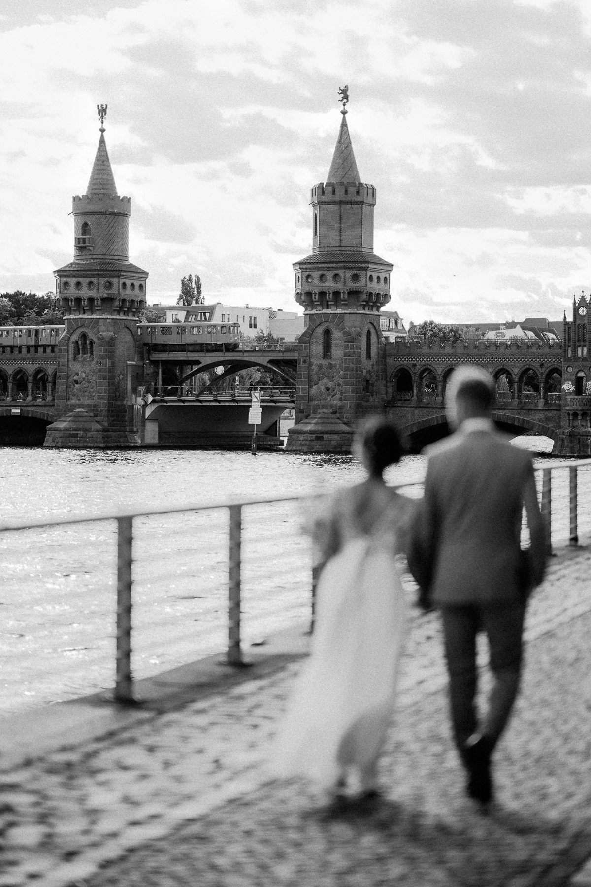 Hochzeit Paarfotoshooting Idee: Oberbaumbrücke ist scharf und Brautpaar unscharf im Vordergrund