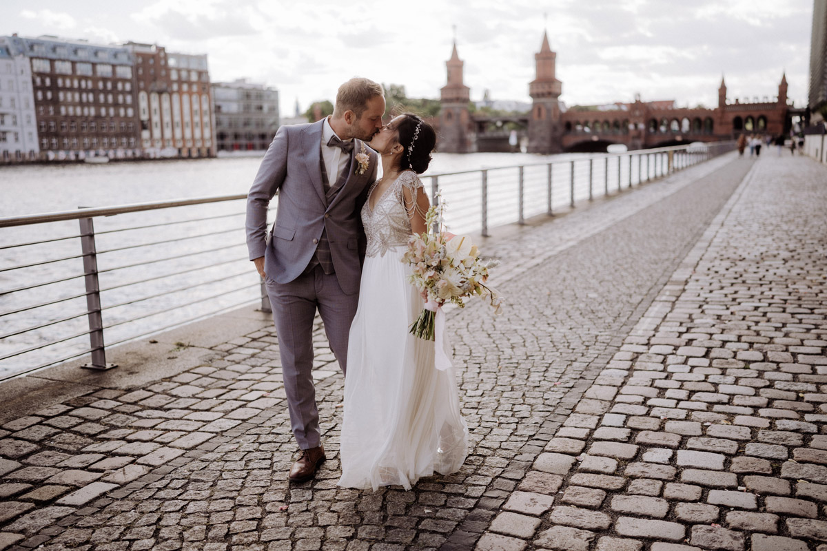 Hochzeitsfotograf und -videograf Team Berlin hält das Paar oft dynamisch im Gehen vor Oberbaumbrücke fest