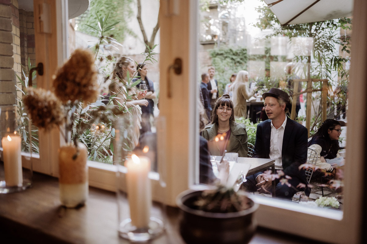 Hochzeitsreportage im heimlichTreu Berlin: Hochzeitsgäste künstlerisch durch Fensterrahmen festgehalten