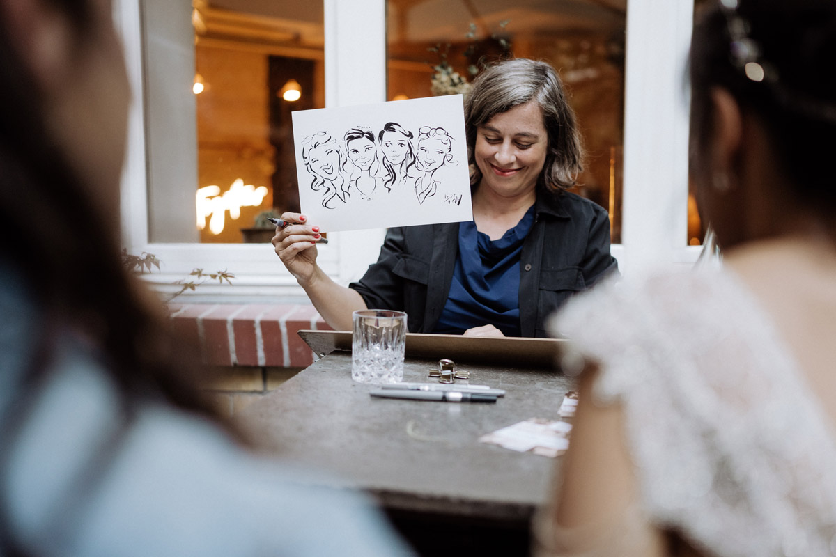 Karikaturistin zeigt auf Hochzeit den Gästen ihr Bild