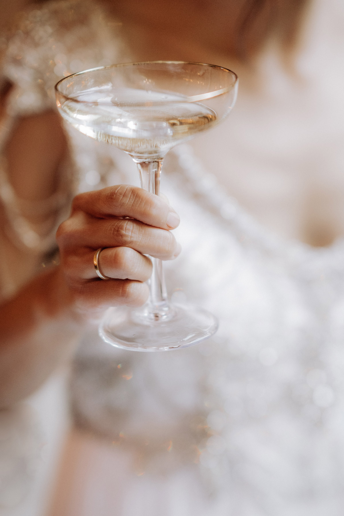 Champagnerglas gehalten von Braut mit Ehering