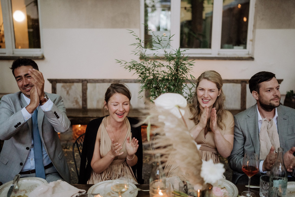 Hochzeitsgäste lachen und klatschen zur Rede