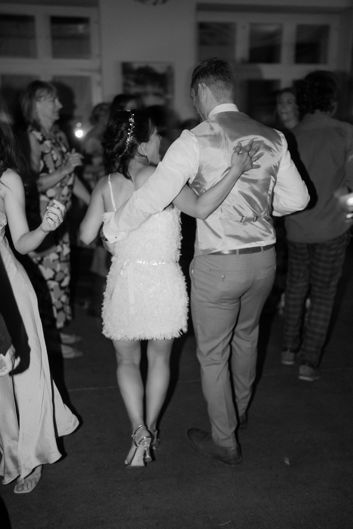 Braut im Second Dress von hinten tanzt Arm im Arm mit Bräutigam zum Abschluss der Hochzeitsreportage im heimlichTreu Berlin mit Foto- und Videoteam