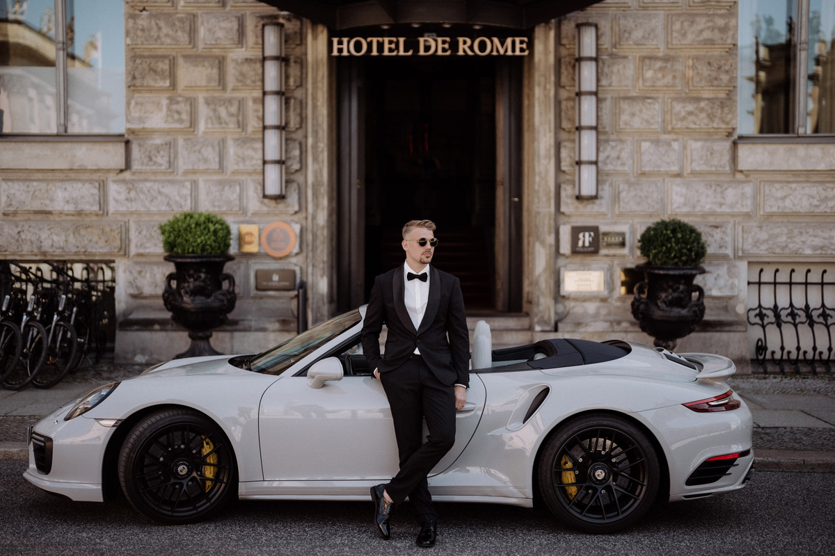 Bräutigam im Standesamt Anzug mit Sonnenbrille wartet an Cabrio gelehnt auf Braut