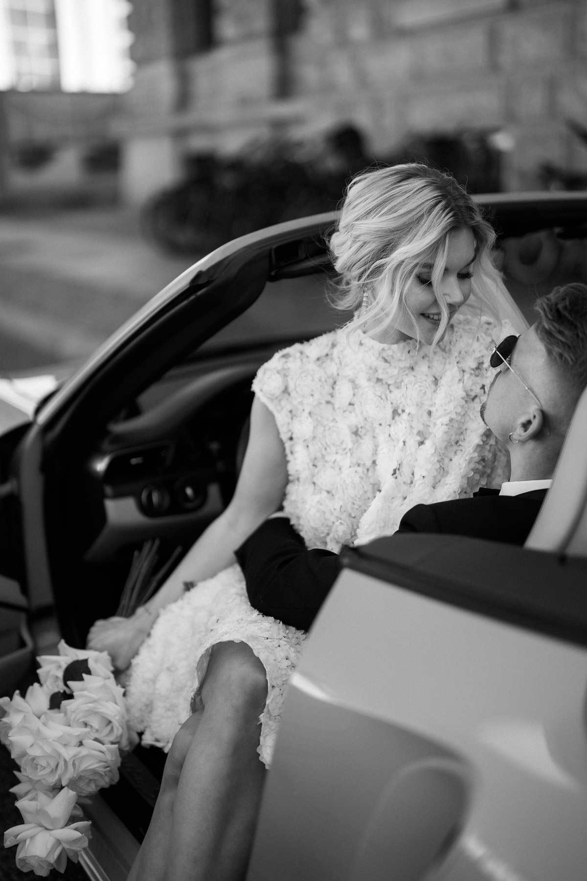 Standesamt Mitte Hochzeitsfotografin lässt Braut natürlich und elegant auf Schoß vom Bräutigam im Hochzeitsauto sitzen