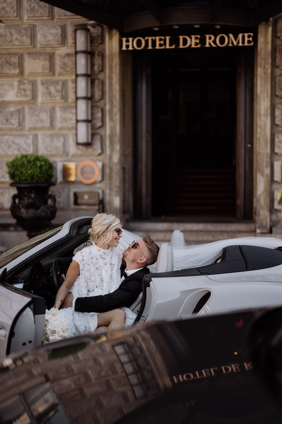 Hochzeitspaar lacht gemeinsam vor Eingang zum Hotel de Rome Berlin