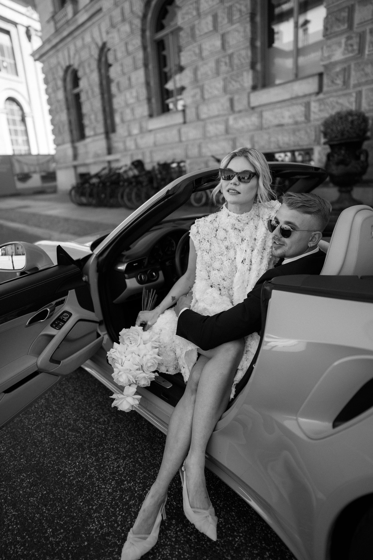 Editorial Hochzeitsfoto der modernen Berlin Mitte Braut in Fashion-Pose sitzend auf Schoß des Bräutigams im Auto