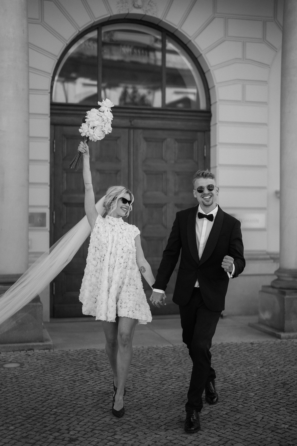 Editorial Hochzeitsfotografie Berlin mit feierndem Bräutigam der frisch verheiratete Ehefrau an der Hand hält