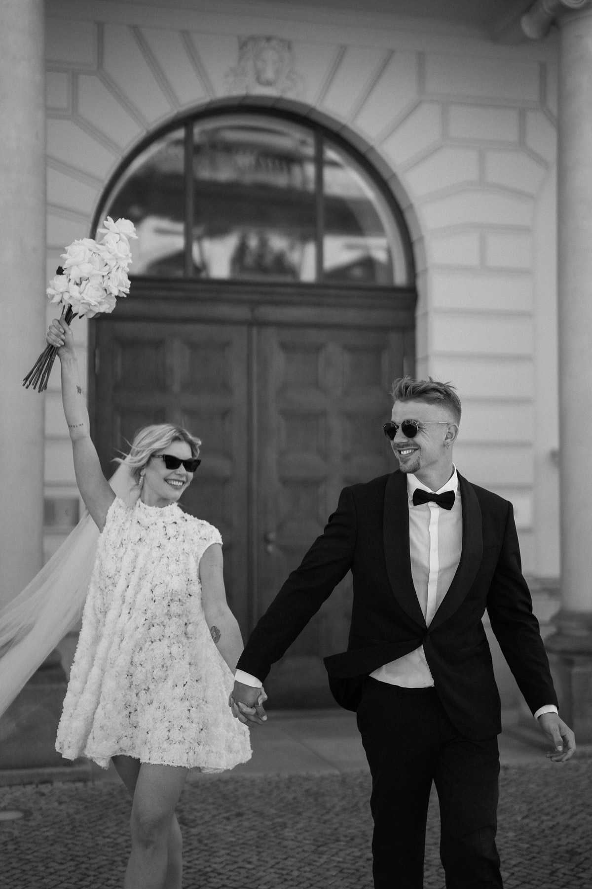 Hochzeitspaar lacht sich an nach Auszug aus Standesamt in Schwarz-Weiß