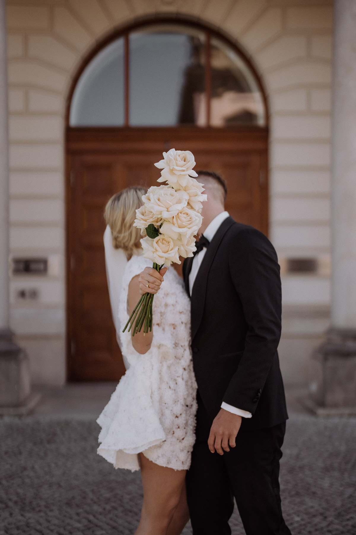 Moderne Standesamt Fotohooting Idee Paar küsst sich hinter Brautstrauß