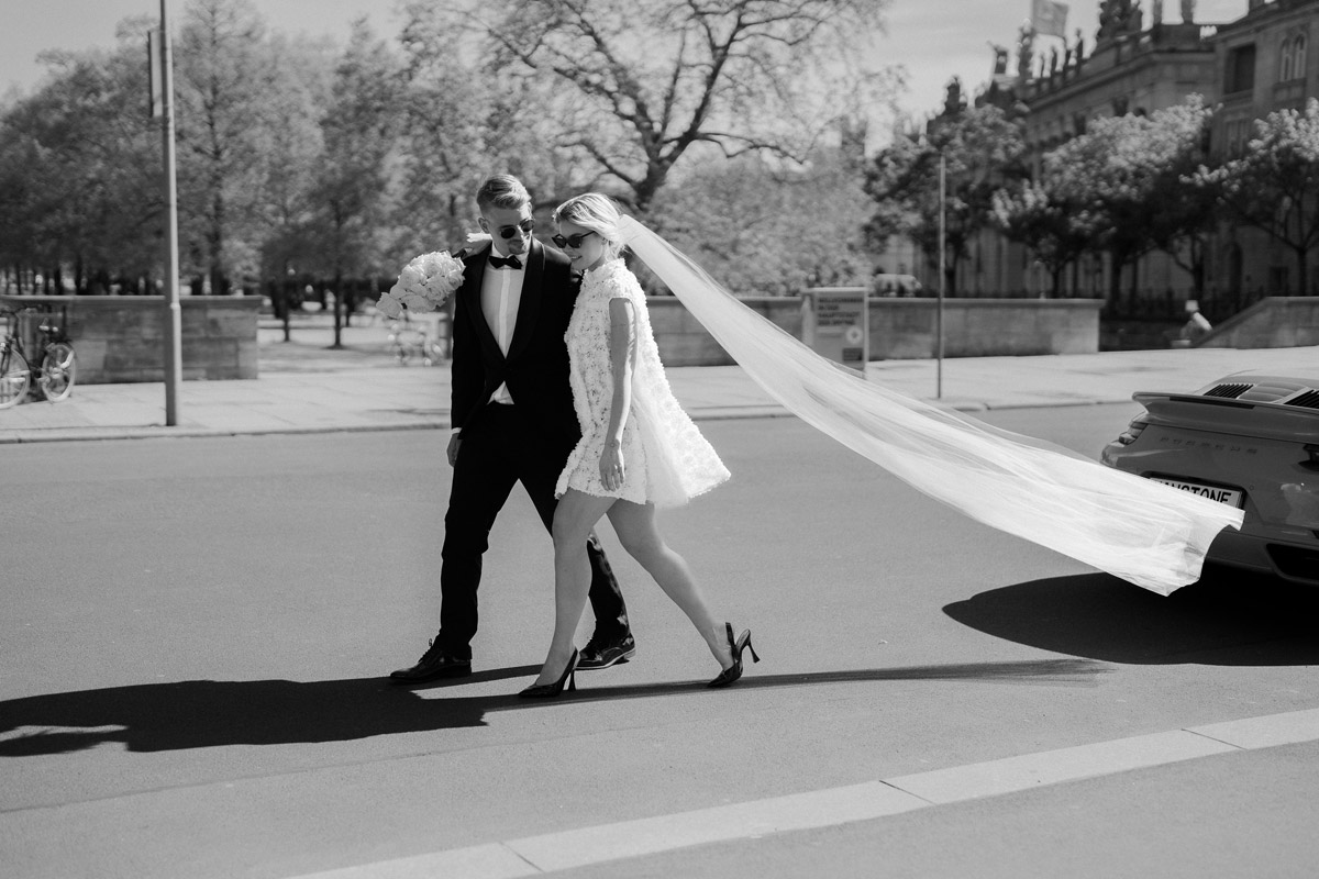 Schwarz-Weiß Hochzeitsfoto im Fashion-Style mit modernem Brautpaar das zum Auto geht