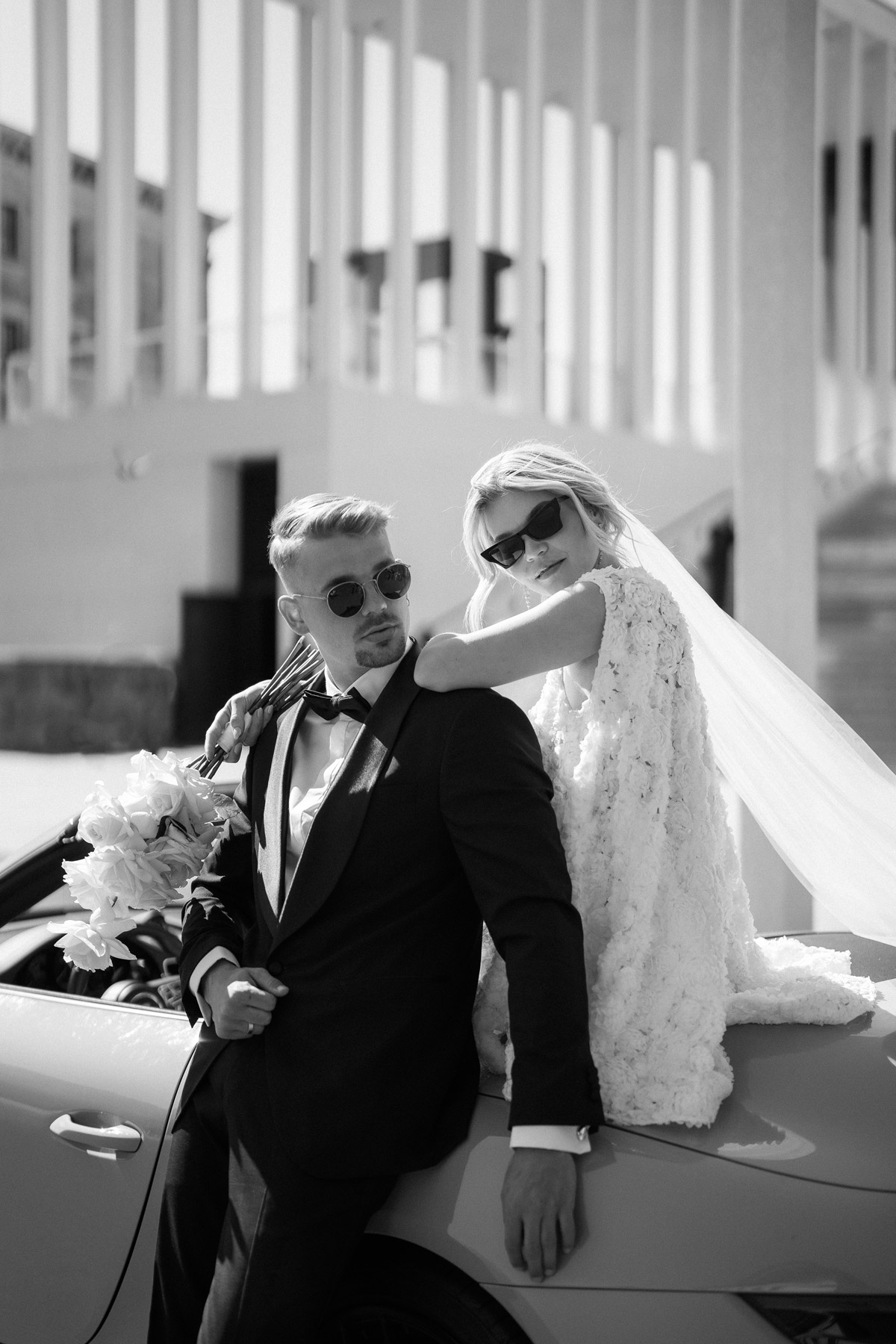 Schwarz-Weiß Hochzeitsportrait: Stylisches Paar am Cabrio, fotografiert von Fashion-Hochzeitsfotografin Melanie Meißner für das Vanity Fair Magazin