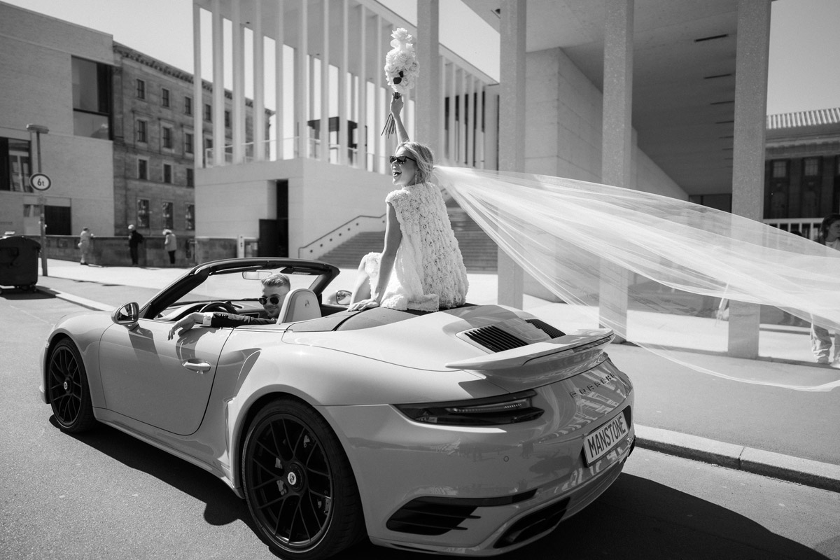 James-Simon-Galerie Hochzeitsfoto mit feierndem Standesamt-Mitte-Brautpaar im Cabrio