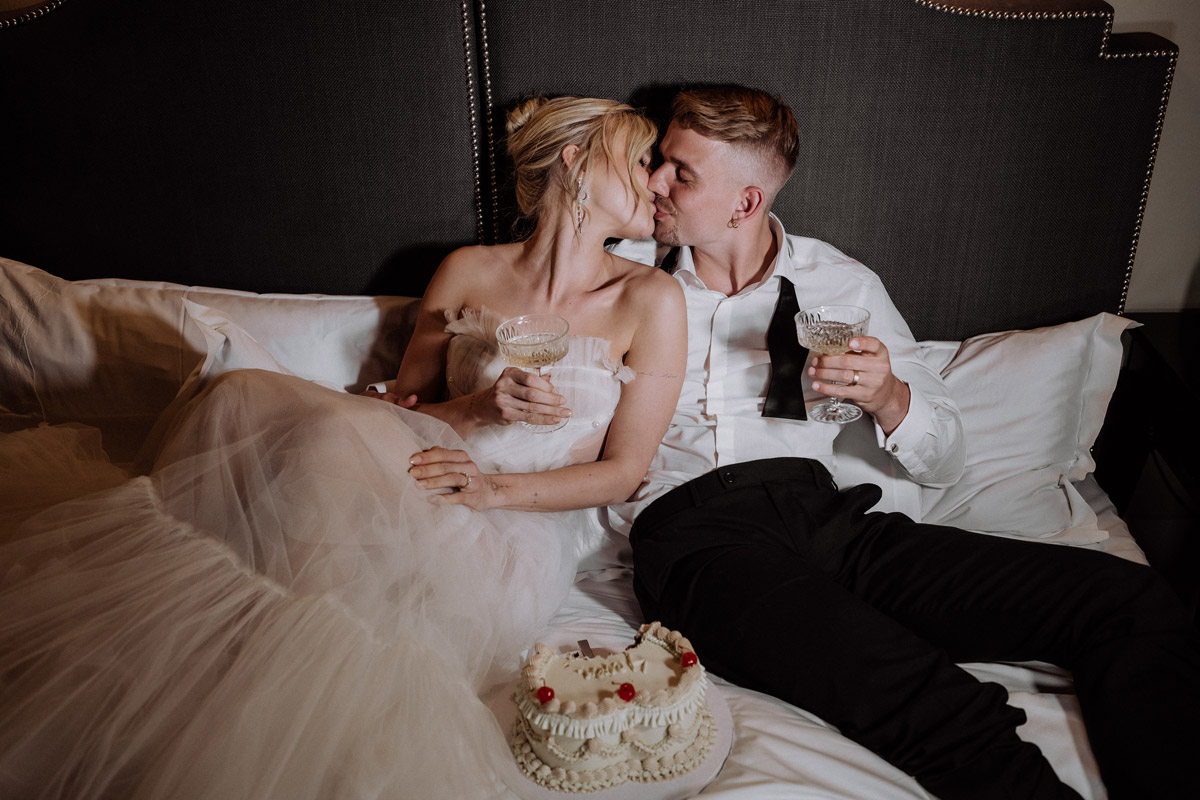 Intime Elopement Hochzeit Berlin: Brautpaar trinkt Champagner im Bett der Hotel de Rome Suite
