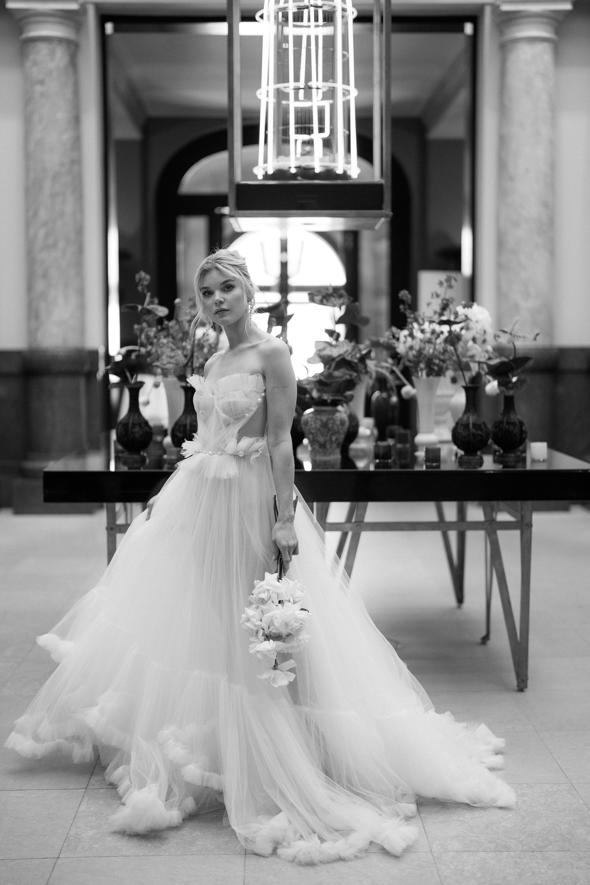 Editorial Hochzeitsfoto: Braut im Ritual Unions Kleid Eva posiert elegant mit Brautstrauß im Hotel