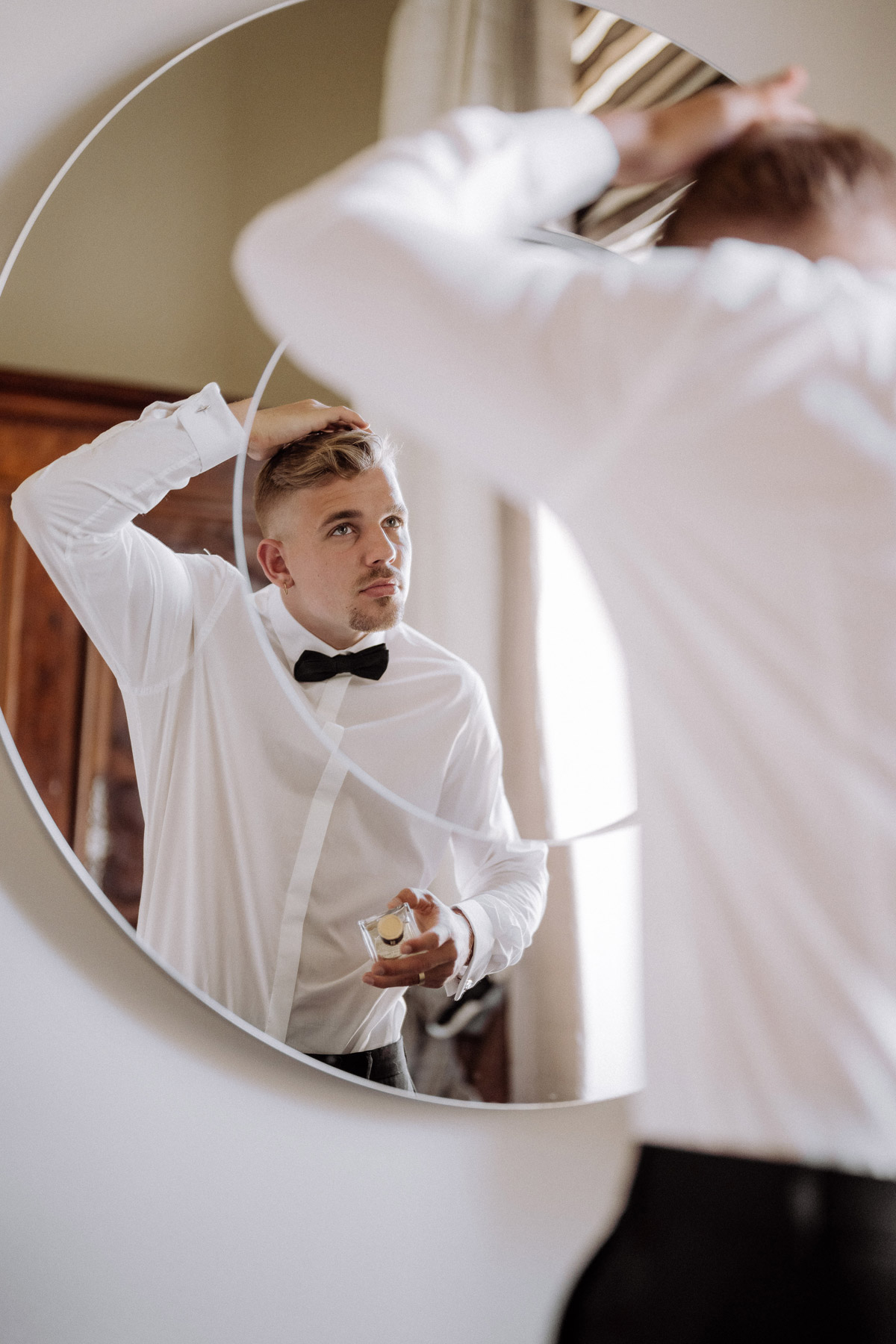 Hochzeitsreportage vom Bräutigam, der seine Haare im Spiegel frisiert