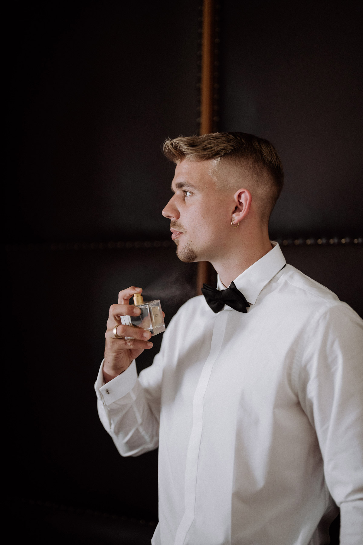 Bräutigam sprüht Parfüm an seinen Hals beim Elopement Berlin