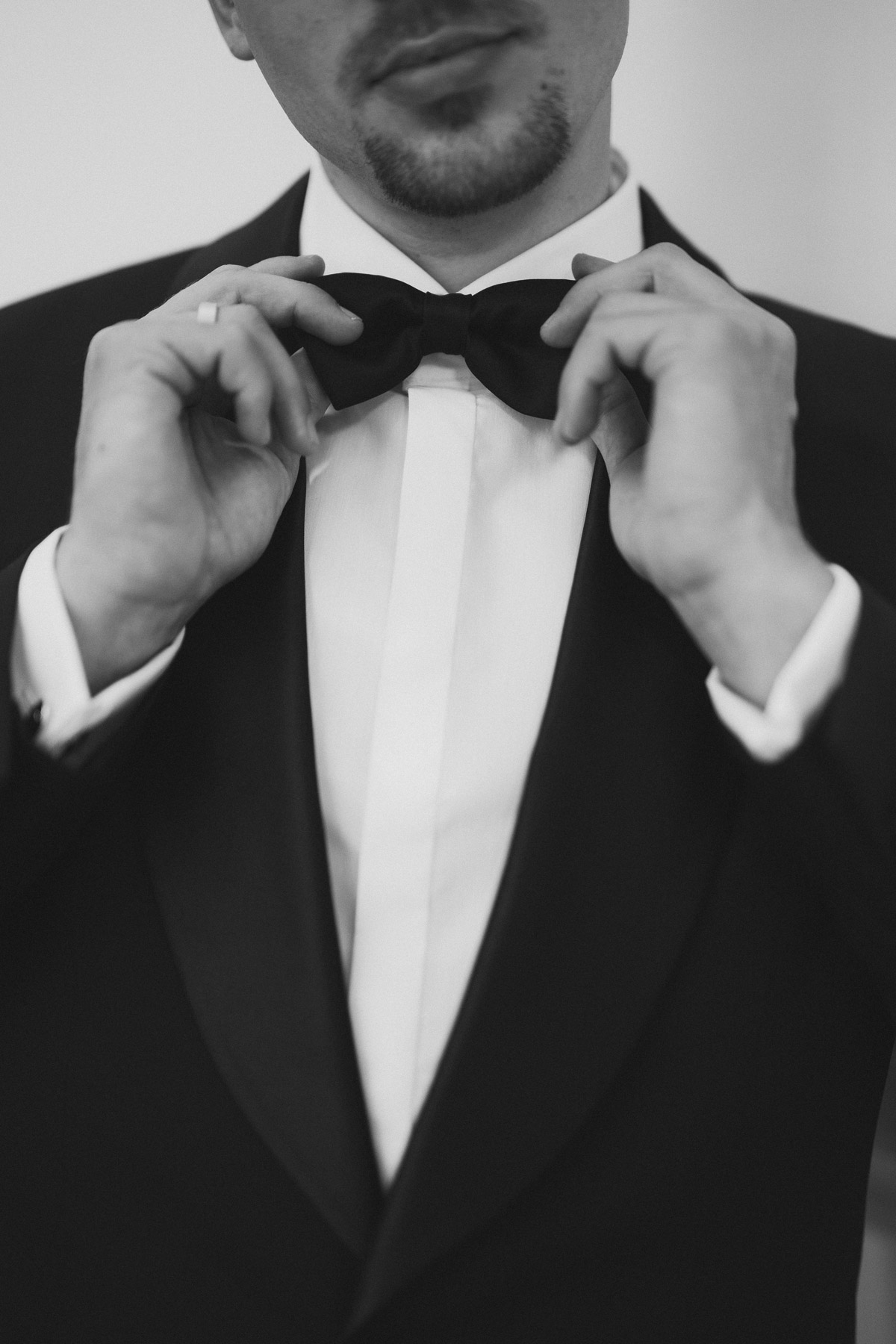 Künstlerisch festgehaltener Hochzeitsmoment: Bräutigam korrigiert Sitz der Fliege