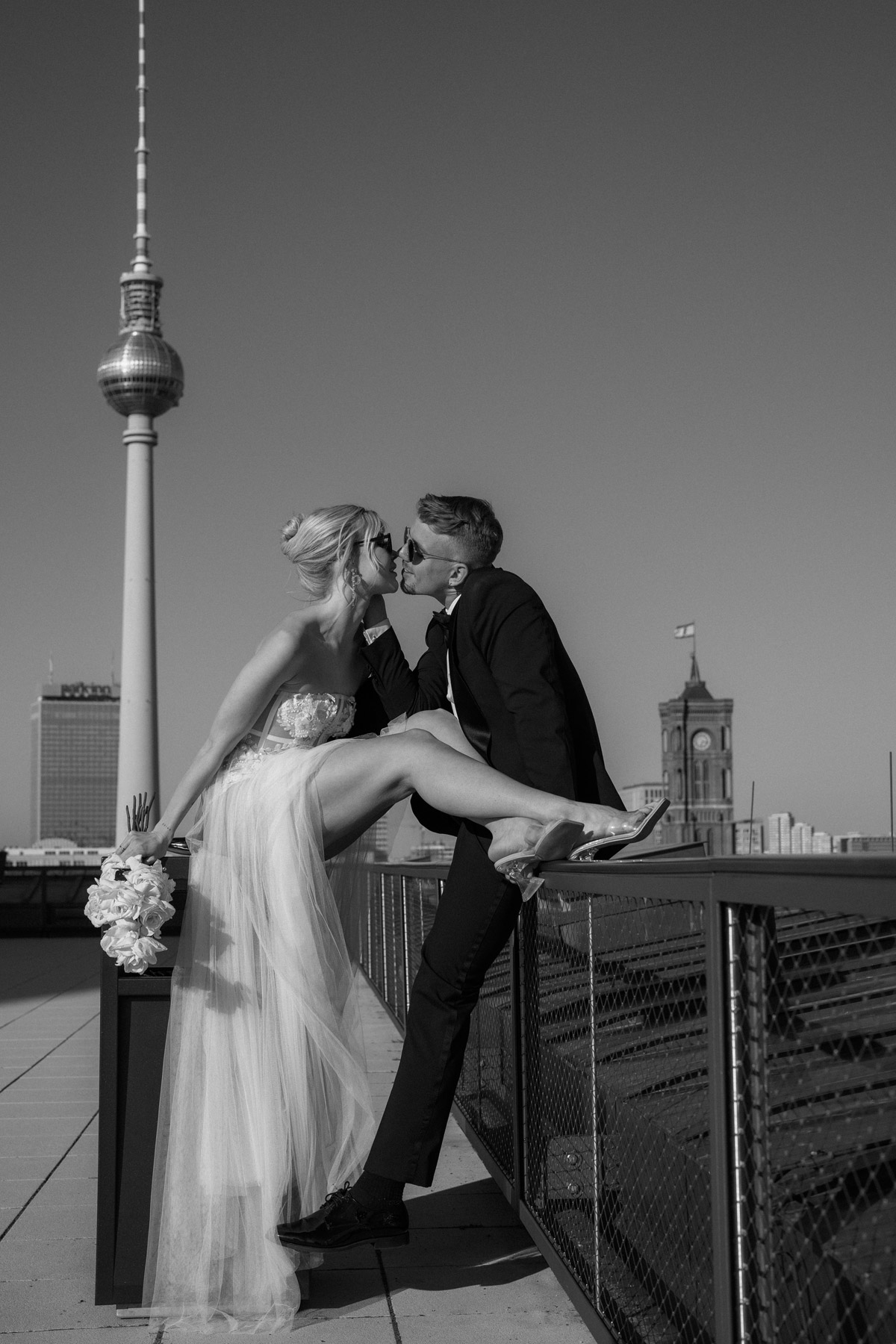 Hochzeitsreportage Berlin mit ungestelltem Moment: Brautpaar küsst sich zwischen Fernsehturm und Rotem Rathaus