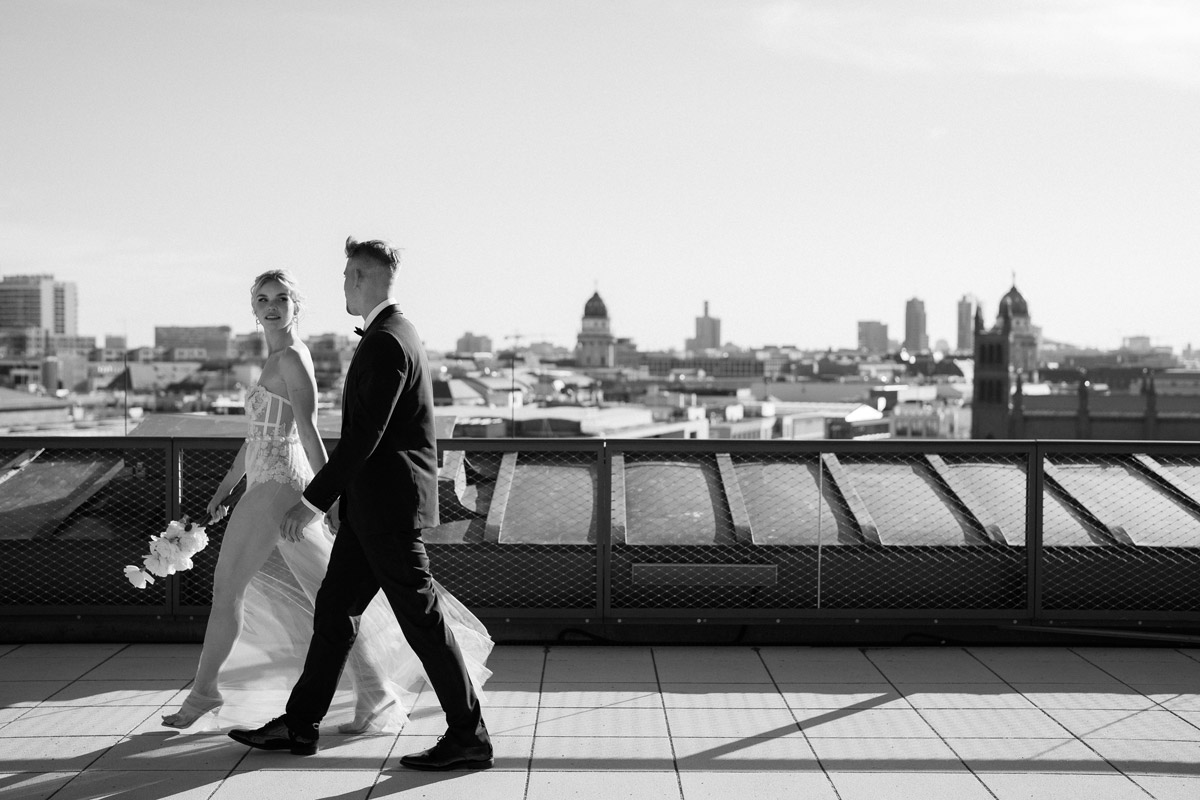 Hochzeitspaar über den Dächern von Berlin in Schwarz-Weiß: Brautpaar läuft über die Dachterrasse