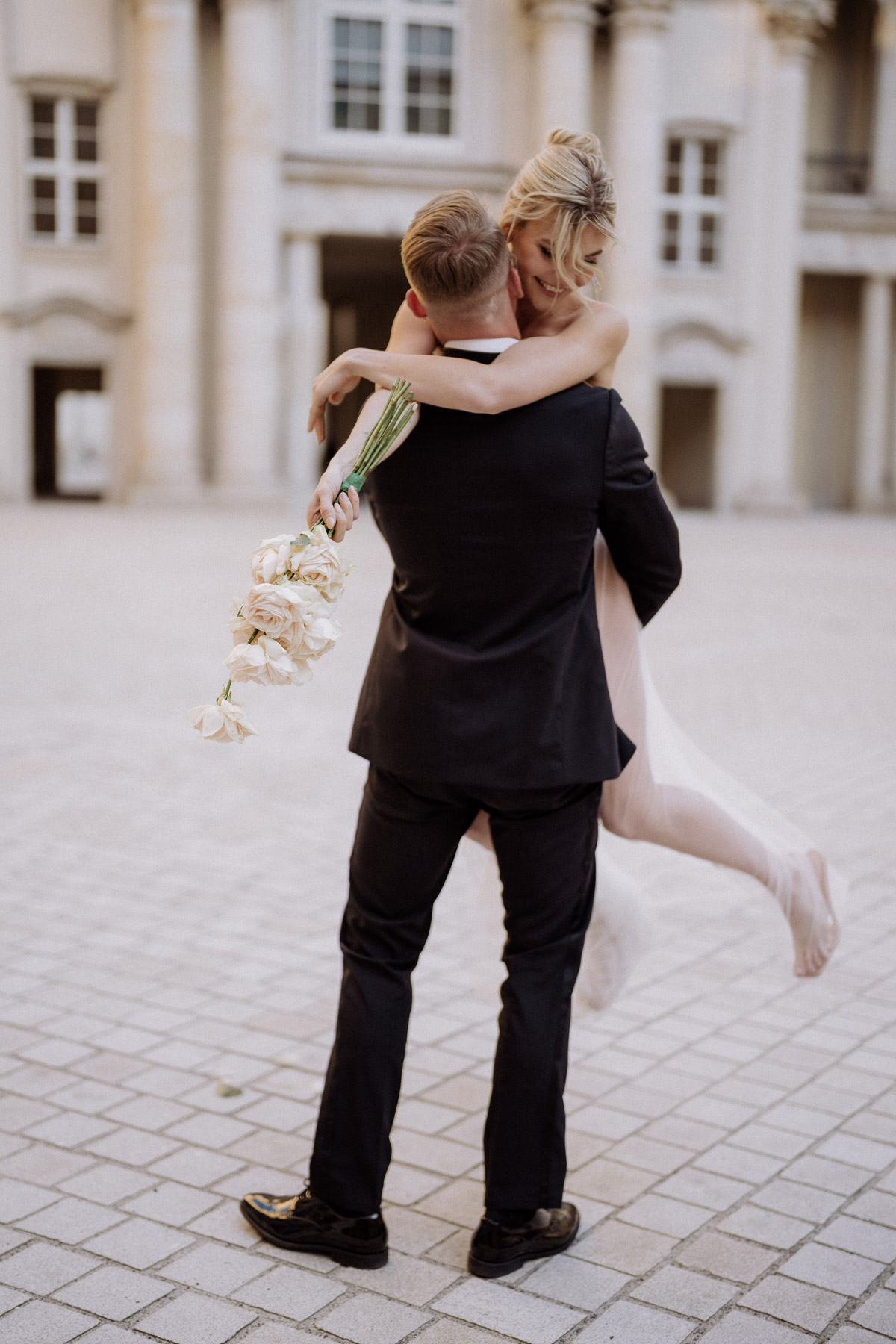 Moderne Hochzeitsfotos in Mitte: Bräutigam hebt Braut hoch und dreht sie