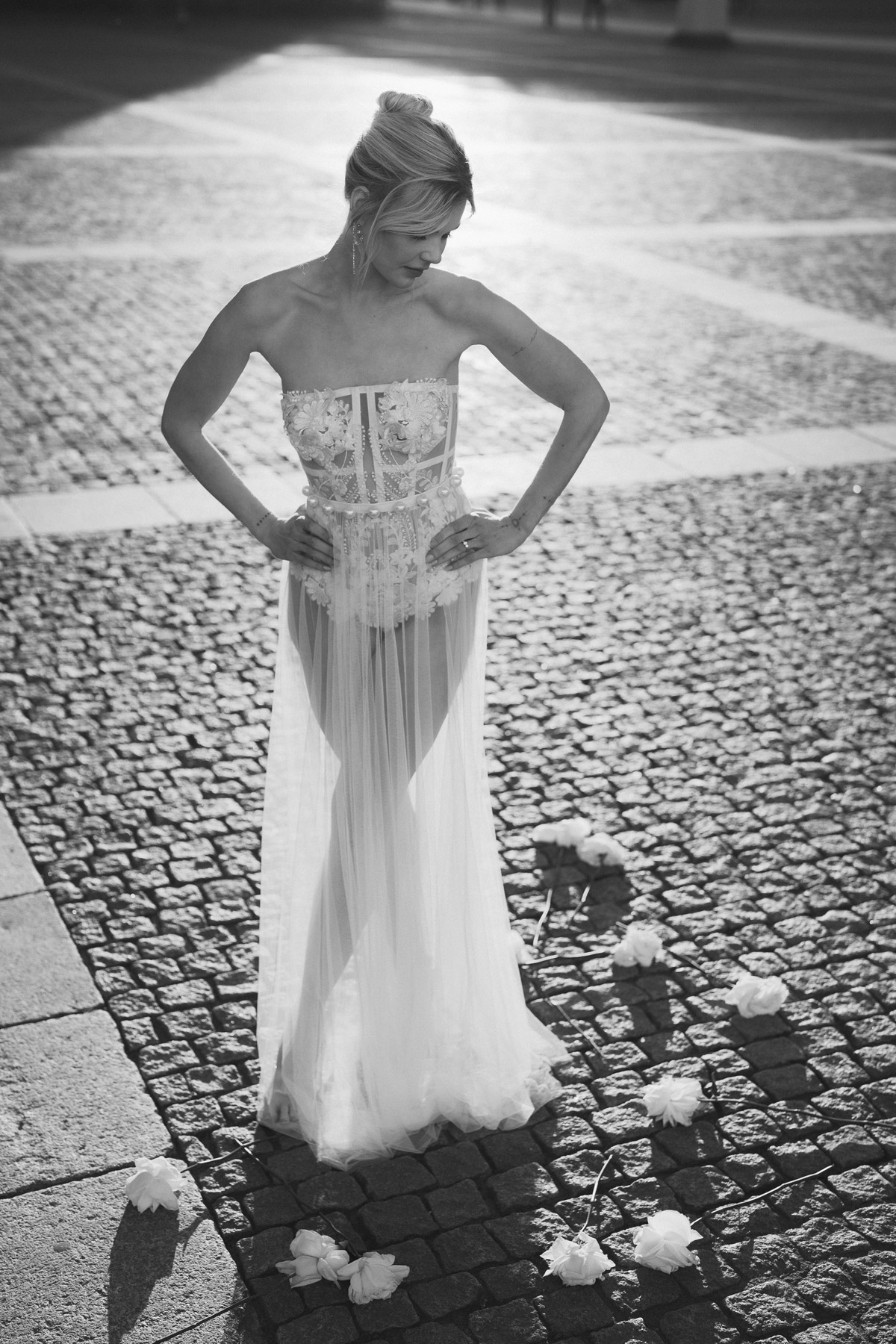 Braut steht auf Bebelplatz und schaut nach unten auf den Boden wo sie weiße Rosen umringen