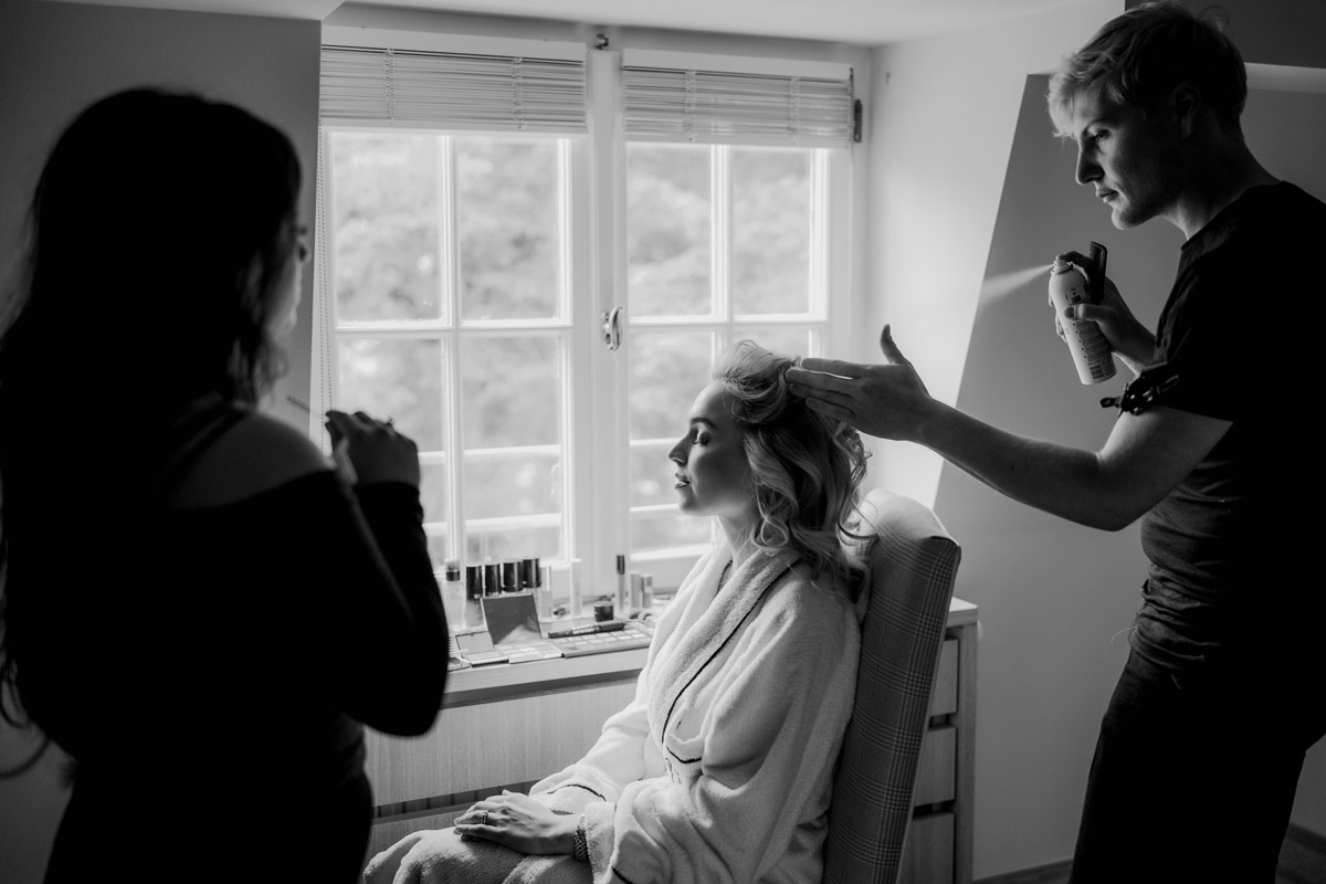 Braut wird am Fenster des Schlosshotels frisiert