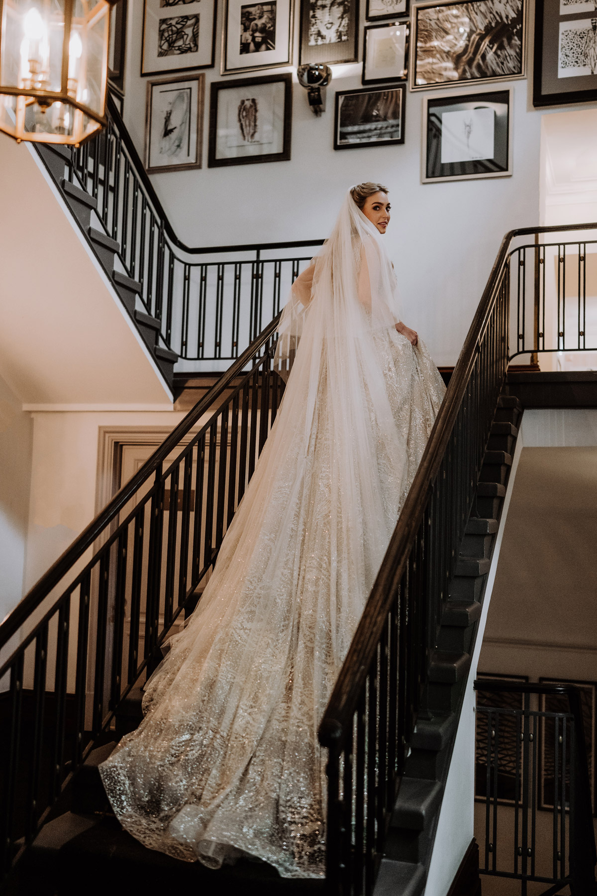 Hochzeit Schlosshotel Grunewald Berlin: Braut mit langer Schleppe steht auf Treppe und schaut über die Schulter