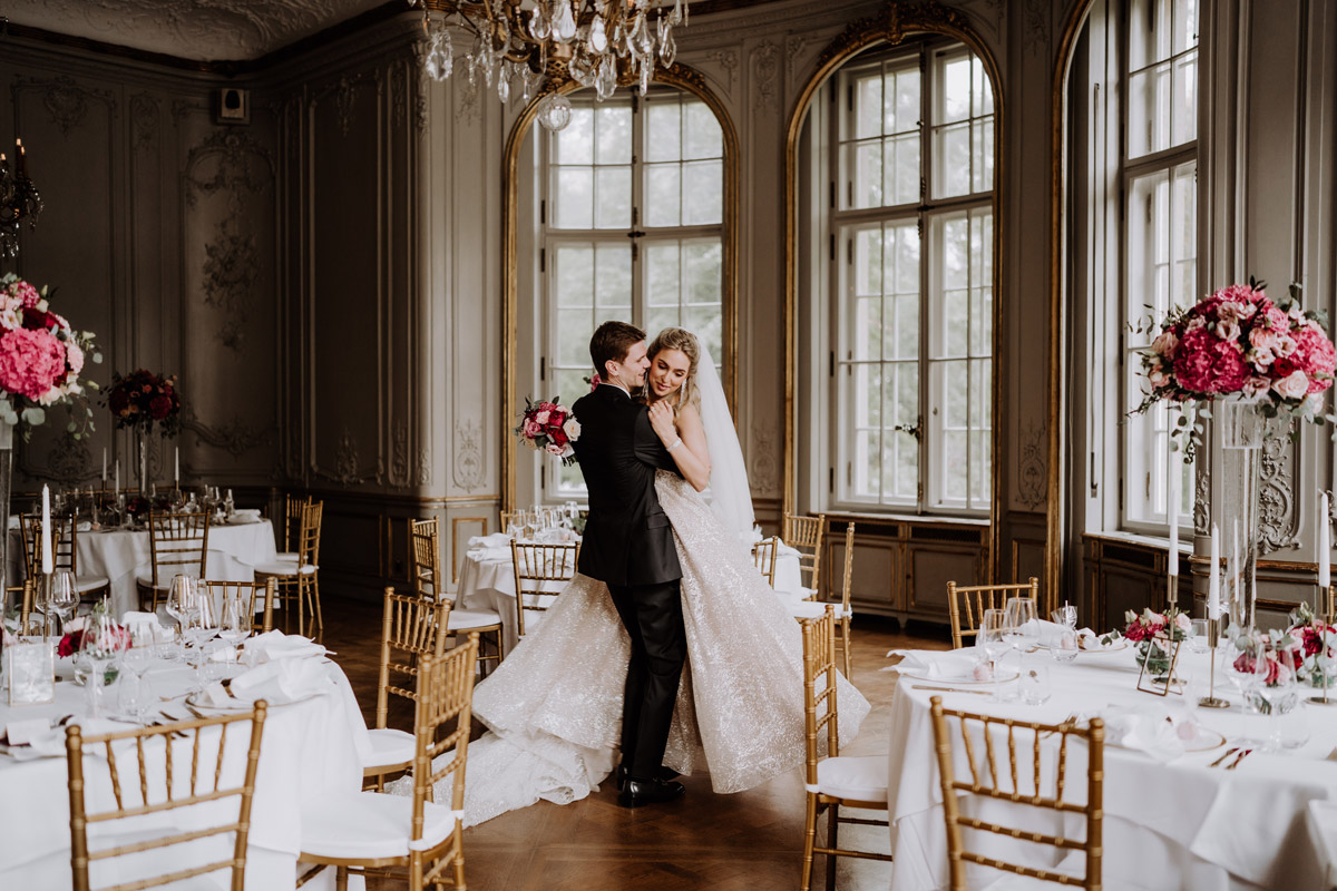 Hochzeitsfotograf und Videograf Schlosshotel Berlin: Ein Bräutigam wirbelt seine Braut im glitzernden Kleid schwungvoll durch den eleganten Festsaal. Genau solche Emotionen in Bewegung entfalten in einem professionellen Hochzeitsvideo mit Originalmusik ihre volle Magie.