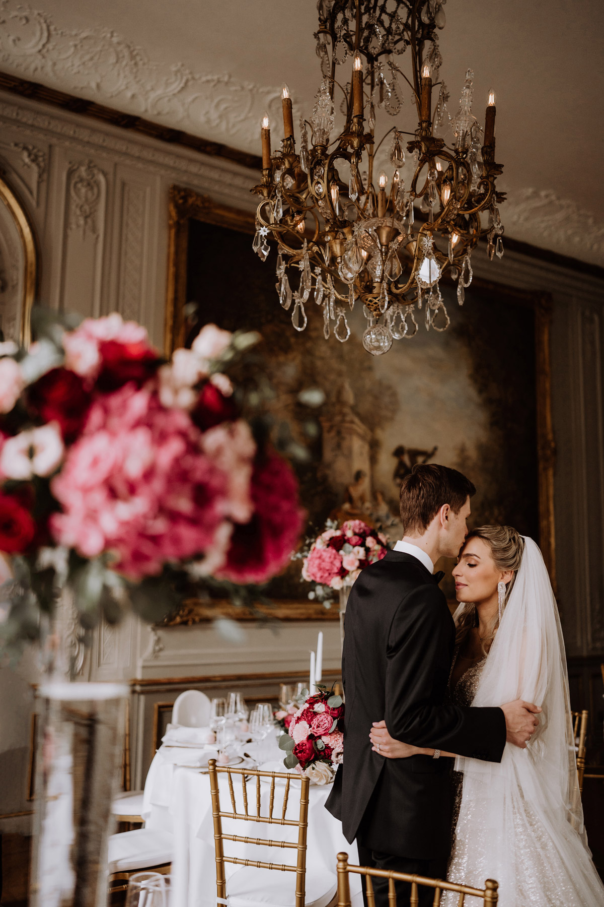 Bräutigam küsst Braut auf Stirn im eleganten Festsaal im Stil der italienischen Renaissance