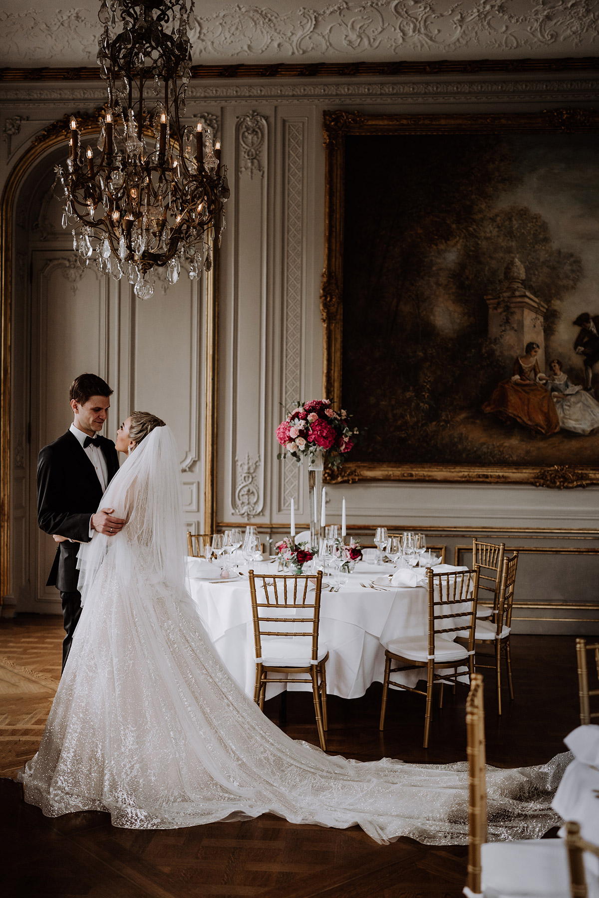 Paar schaut sich im Feiersaal des Schlosshotels an, umgeben von runden Tischen mit goldenen Stühlen