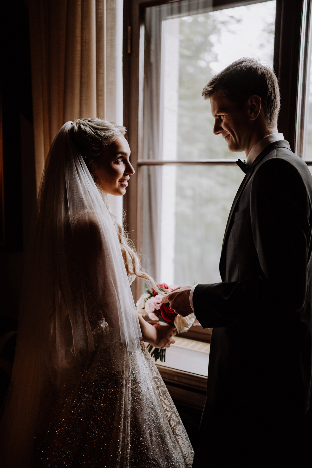 Brautpaarfotoshooting bei Regenhochzeit: Bräutigam spielt mit Haar der Braut