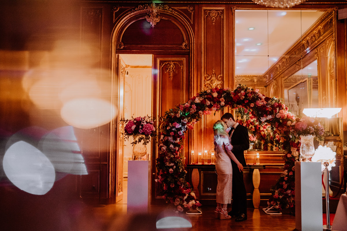 Brautpaar küsst sich unter Blumenbogen im Schlosshotel Berlin