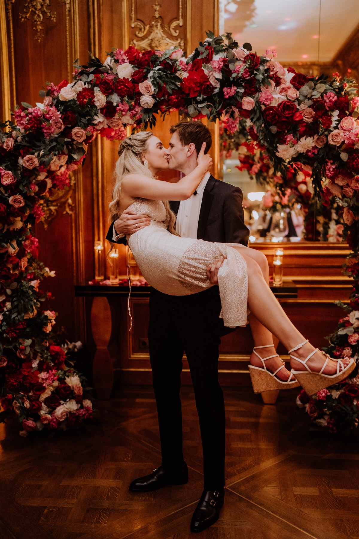 Hochzeitspaar küsst sich unter Traubogen auf Hochzeitsparty im Schlosshotel Grunewald Berlin