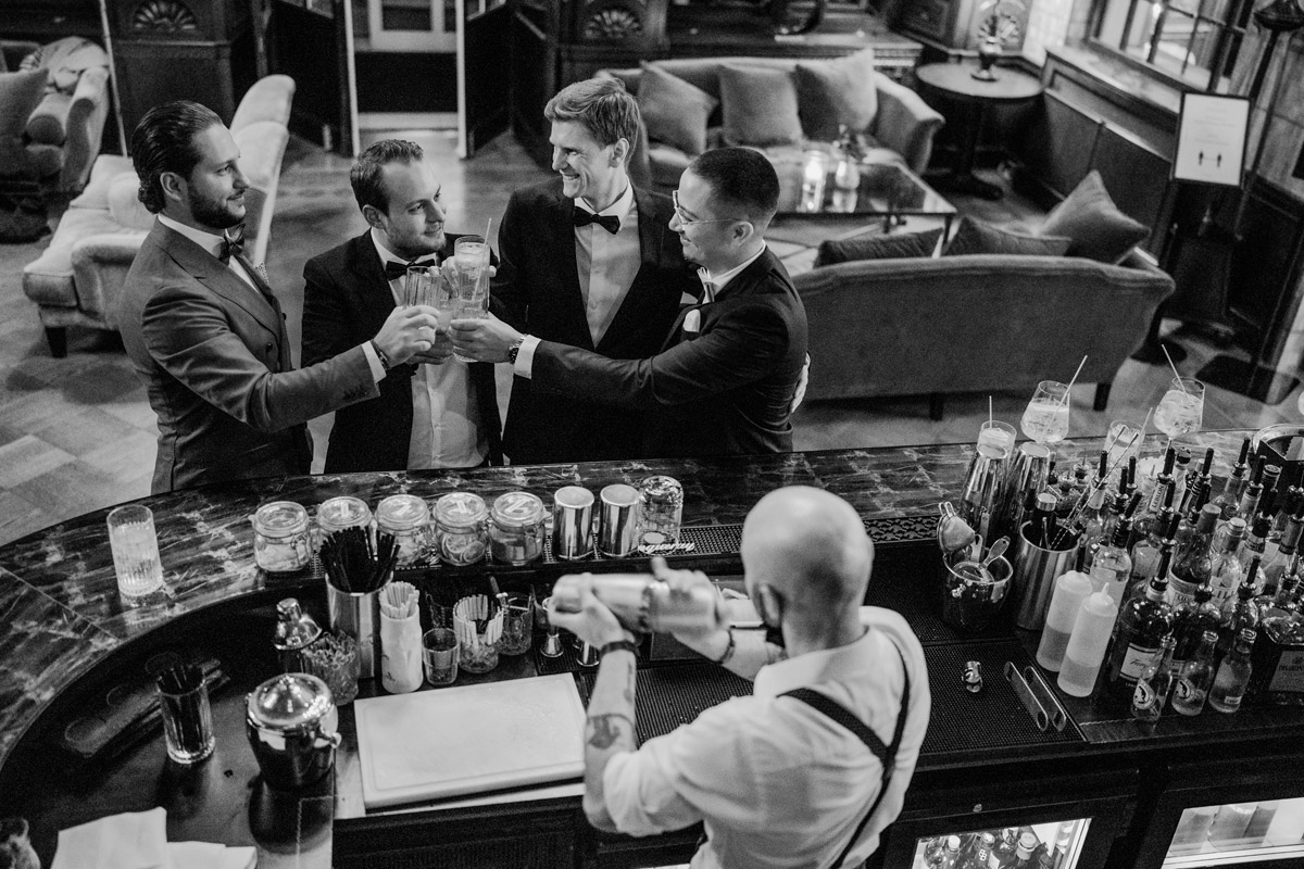 Bräutigam stößt mit Freunden an der Bar in der Hotellobby an