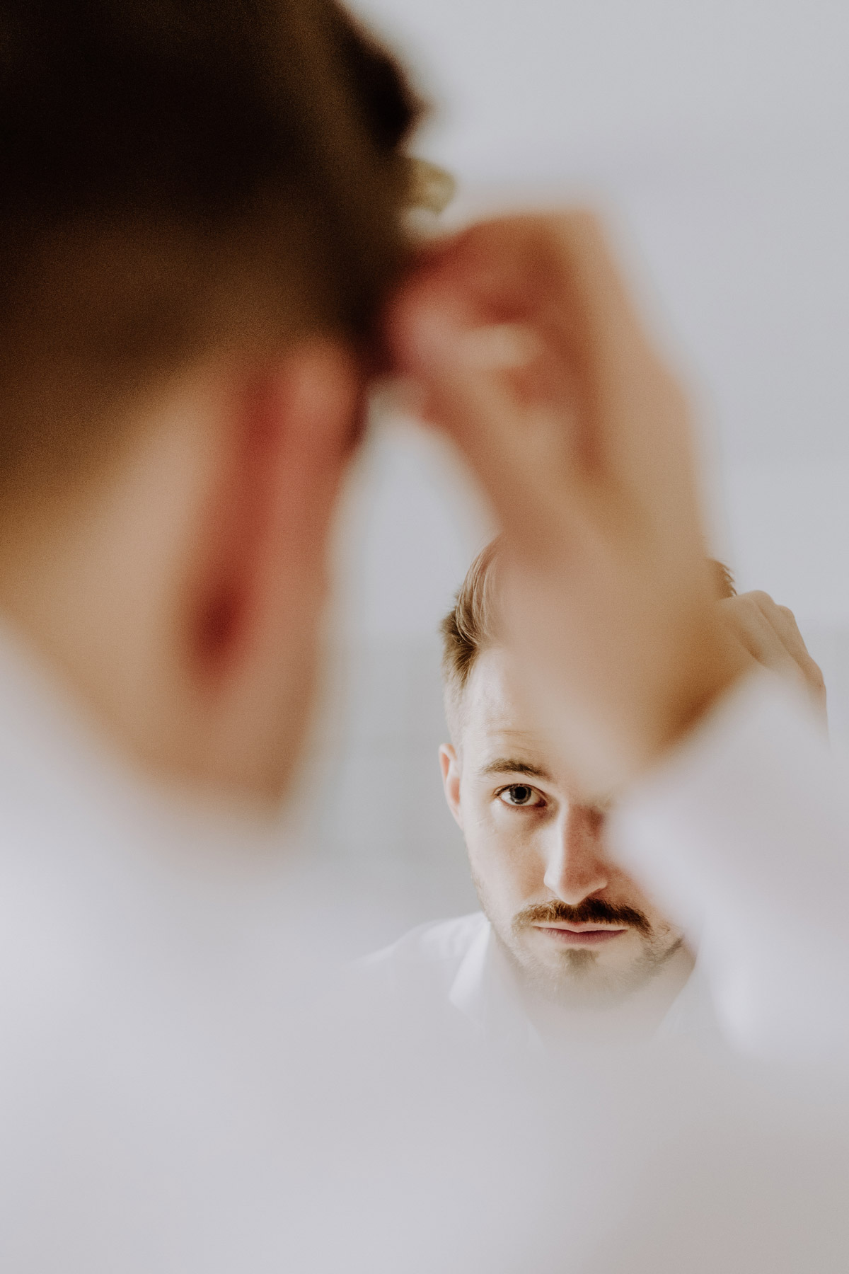 Bräutigam schaut in den Spiegel, um Haare zu frisieren
