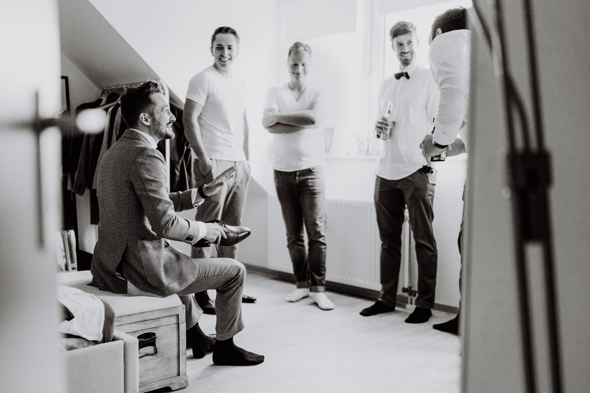 Bräutigam zieht Schuhe an und Freunde schauen zu