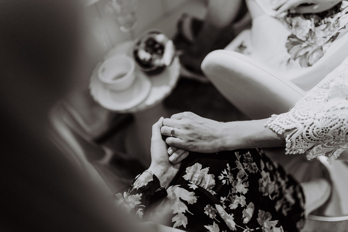 Detailaufnahme: Trauzeugin hält die Hand der aufgeregten Braut in Schwarz-Weiß