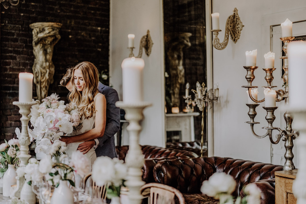 Brautpaar-Fotoshooting am Hochzeitstisch der Hochzeitsplaner Braut mit rosa Pfingstrosen in Feierlocation