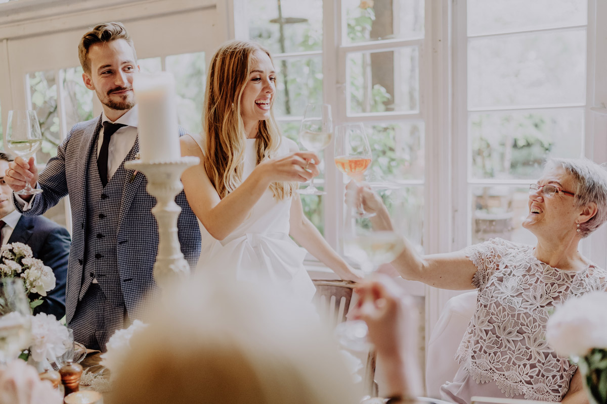 Brautpaar stößt mit Gästen auf die Hochzeit an