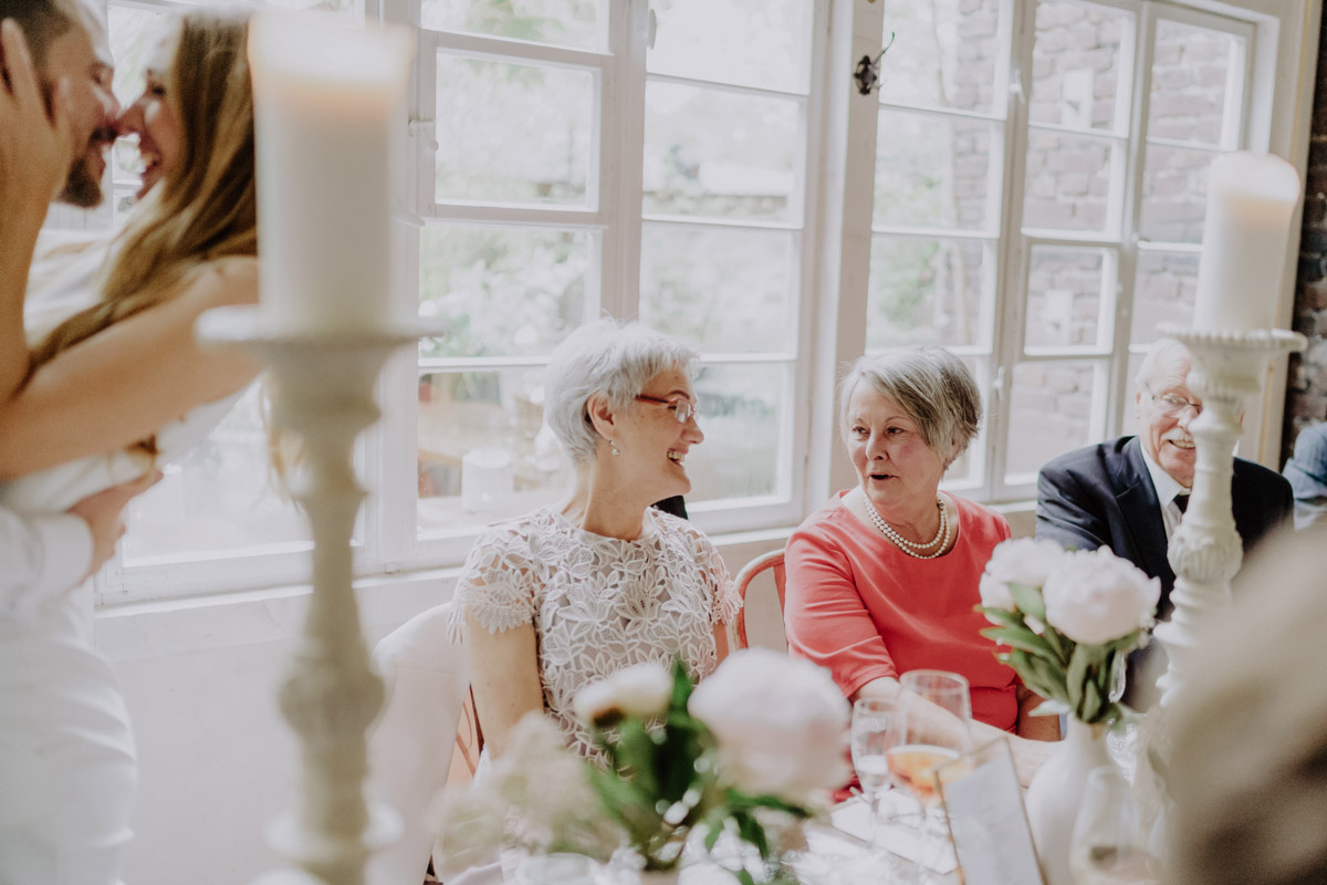 Gäste unterhalten sich währen Paar sich küsst