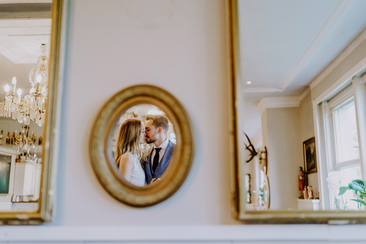 Kreatives Hochzeitsfoto: Paar küsst sich über einen runden Spiegel fotografiert