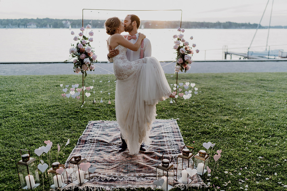 Hochzeit Gästehaus Blumenfisch: Brautpaar steht im Boho-Stil am Ufer des Großen Wannsee in Berlin
