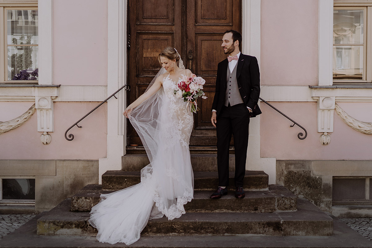 Romantisches Brautpaarfoto vor rosa Haus in Potsdam passend zum Boho Brautstrauß