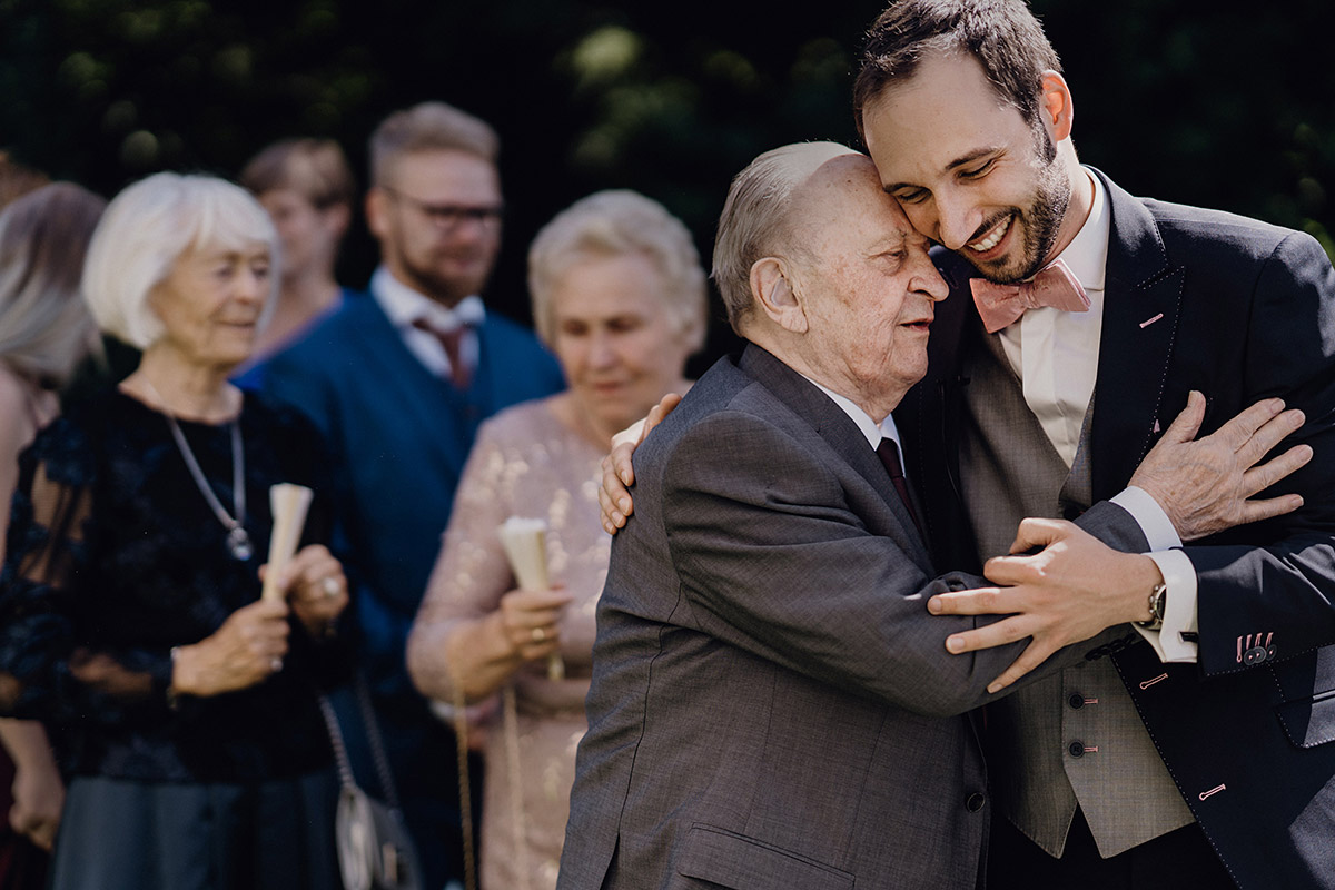 Opa gratuliert und drückt Bräutigam - authentische Hochzeitsfotografie Berlin